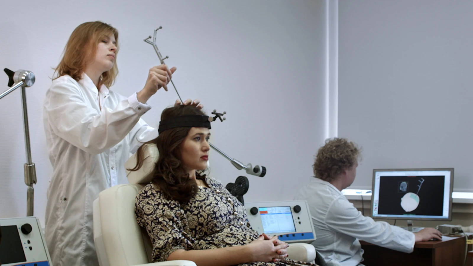 Clinician positioning equipment beside a seated participant in a transcranial magnetic stimulation laboratory